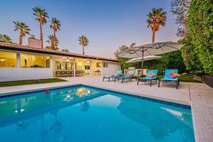 una piscina con due sedie e una casa di The Palm Diamond a Luxury Poolside and Golf Oasis a Palm Springs
