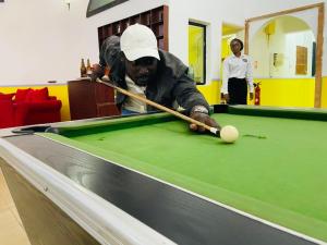a man playing pool with a cue on a pool table at Hôtel chez Marie Oyouma in Port-Gentil +19 photos