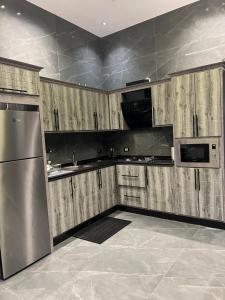 une cuisine avec des armoires en bois et un réfrigérateur en acier inoxydable dans l'établissement Villa Ohaio, à Amman