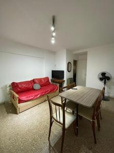 un salon avec un canapé rouge et une table dans l'établissement Departamento frente al mar, à Necochea