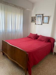 une chambre avec un grand lit recouvert d'une couverture rouge dans l'établissement Departamento frente al mar, à Necochea