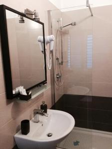 een badkamer met een wastafel en een douche met een spiegel bij B&B La Stazione in Acquaviva delle Fonti