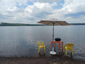 two chairs and a table with an umbrella in the water at Rancho Carvalho in Alexânia