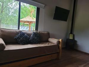 a couch with pillows sitting in a living room with a window at Cabaña premium! in Villa Anizacate