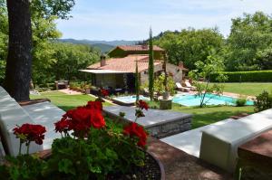 a house with a swimming pool and red flowers at Sestuccia in Gaiole in Chianti