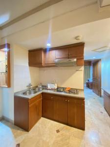 une cuisine avec des armoires en bois et un évier dans l'établissement Thomas Coastal Apartment at Jayakarta Residence, à Seminyak
