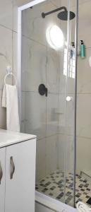 a shower with a glass door in a bathroom at Stay-Tiah Whyte, Durban in Durban