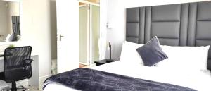 a bedroom with a white bed and a black chair at Stay-Tiah Whyte, Durban in Durban