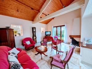 ein Wohnzimmer mit einem roten Sofa und Stühlen in der Unterkunft Villa Mousse, Maison 4Ch 6 Lits à 17 min du Futuroscope in La Celle-sous-Gouzon