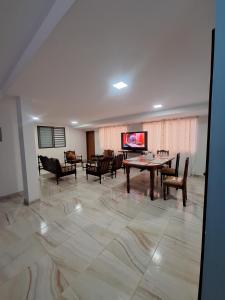 un salon avec une table, des chaises et une télévision dans l'établissement La última parada del Alauseño, à Alausí