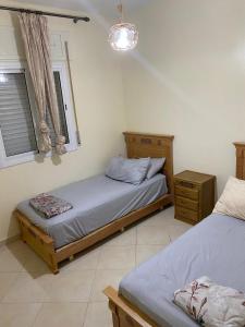 Un dormitorio con dos camas individuales y una ventana. en Gzenaya, en Tánger
