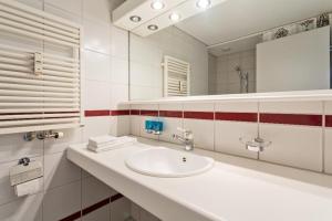 a white bathroom with a sink and a mirror at Golf Ranch, 1Er Stock in Ascona +13 photos