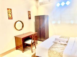 a bedroom with a desk and a bed and a mirror at Puspa Guest House Lembongan in Nusa Lembongan