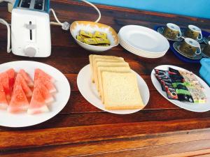 a wooden table with plates of sandwiches and watermelon at Puspa Guest House Lembongan in Nusa Lembongan