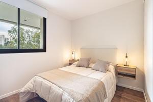 a white bedroom with a bed and a window at Departamento parque Saavedra in La Plata
