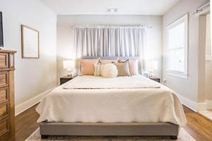 a white bedroom with a large bed with pillows at Owen Bungalow II - OKC Paseo - HOT TUB & Fire Pit in Oklahoma City