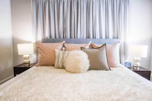 a bedroom with a white bed with pillows and two lamps at Owen Bungalow II - OKC Paseo - HOT TUB & Fire Pit in Oklahoma City