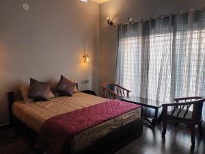 ein Schlafzimmer mit einem Bett und einem Tisch und einem Fenster in der Unterkunft Grand Sapphire Resorts & Travels Idukki in Idukki
