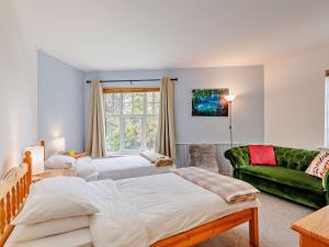 a bedroom with two beds and a green couch at 3 Bed in Machynlleth 93080 in Cemmaes