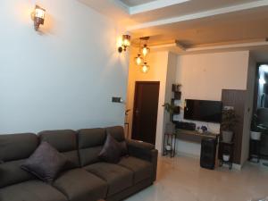 ein Wohnzimmer mit einem braunen Sofa und einem TV in der Unterkunft Grand Sapphire Resorts & Travels Idukki in Idukki