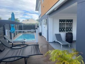 a patio with a pool and chairs and a house at L'améthyste in Saint-François