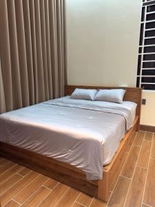 a bed in a room with a white bedsheet and curtains at Cozy Home for Family, Friends & Work Trips in Buon Ma Thuot