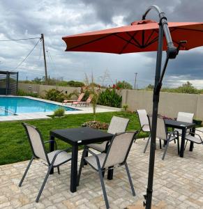 a table and chairs with an umbrella next to a pool at EuniBot Guest House in Francistown