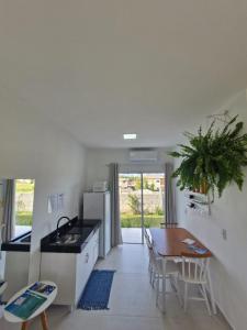 a kitchen and dining room with a table and a refrigerator at Palo Santo - Praia do Rosa in Praia do Rosa