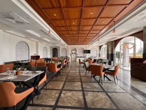 a dining room with tables and chairs and windows at Hotel Mumbai House Pithampur in Mhow