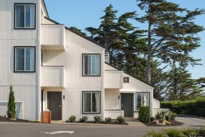 a white house with black doors and trees at Hotel Dega in Bodega Bay