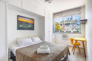 a bedroom with a bed and a desk and a window at Cobertura posto 5 in Rio de Janeiro