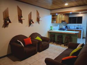 a living room with two couches and a kitchen at Casa Abril - La Fortuna in Fortuna