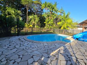a swimming pool in a backyard with a fence and trees at La Villa Louisia in Matoury