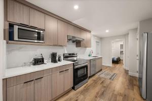 a kitchen with stainless steel appliances and wooden cabinets at Peaceful 2BR Getaway with Fireplace & Parking Basement Suite in Abbotsford