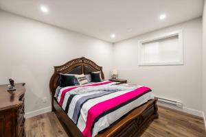 a bedroom with a bed with a wooden frame and a window at Peaceful 2BR Getaway with Fireplace & Parking Basement Suite in Abbotsford