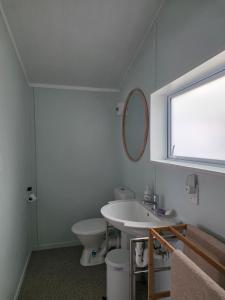 a bathroom with a sink and a toilet and a window at Captains Quarters in Ohope Beach +1 photo