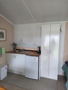 a kitchen with white cabinets and a sink at Captains Quarters in Ohope Beach