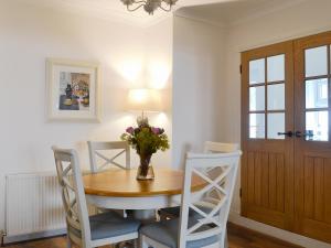 ein Esstisch mit Stühlen und einer Vase mit Blumen in der Unterkunft Raglan Cottage in Ardentinny