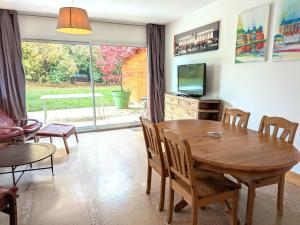 a living room with a wooden table and a television at Gîte au Calme Proche de Nancy avec Terrasse Privative et Parking - FR-1-584-103 in Champenoux