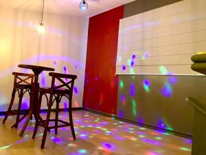 two chairs and a table in a room with purple lights at Blue Suítes - motel in Cascavel