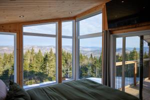 a bedroom with a large window with a view of the mountains at Horizon - plein air et détente in Lac-Beauport +3 photos