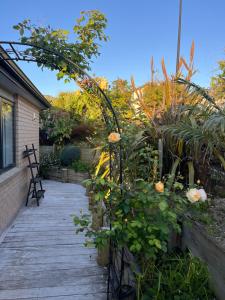 a wooden walkway with flowers and plants on it at Peaceful house in Kumeu