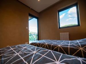 two beds in a room with two windows at Mountain-view eco-friendly cottage in Marcoux