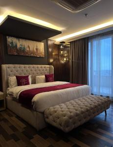a bedroom with a large bed with a ottoman in it at Goldcrest Alfatah Mall - DHA Phase 4 - Luxury Apartments by Alvis Suite in Lahore