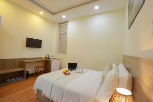 a bedroom with a bed and a desk and a television at Khách sạn Pine Hill Hotel Dalat in Da Lat