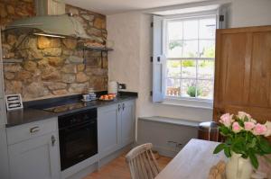 a kitchen with a table and a stone wall at Sea Haze Charlestown in St Austell