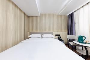 Un dormitorio con una cama blanca grande y una mesa en Chenlong Cafe Hotel, en Guangzhou