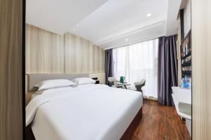 Una habitación de hotel con una cama blanca y un escritorio. en Chenlong Cafe Hotel, en Guangzhou 32 fotos más