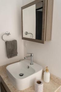 ein Badezimmer mit einem weißen Waschbecken und einem Spiegel in der Unterkunft Departamento Acapulco Diamante in Acapulco + 29 Fotos