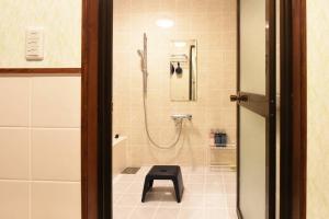 a bathroom with a shower with a stool in it at ORENCHii in Yomitan